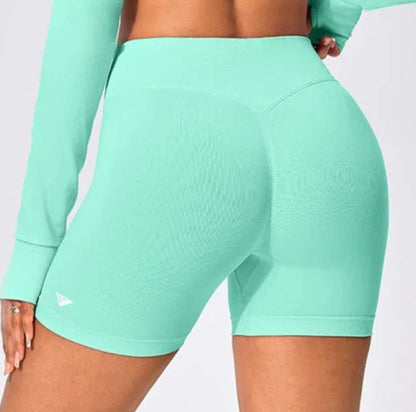Back view of Aura Halter Shorts Set in mint green, featuring seamless body-sculpting training shorts with a high-waisted V-contour waistband, booty scrunch detail, and a minimal brand logo on the left leg.