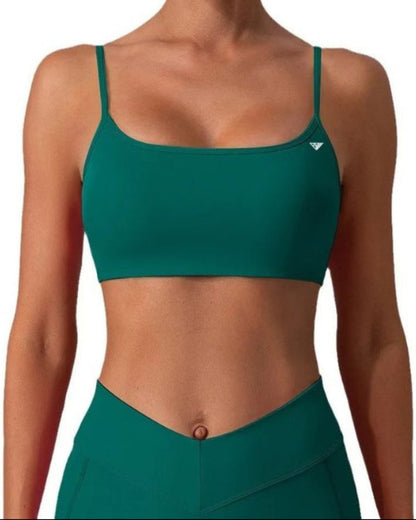 A woman wearing a teal green sports bra and matching high-waisted leggings against a plain white background.