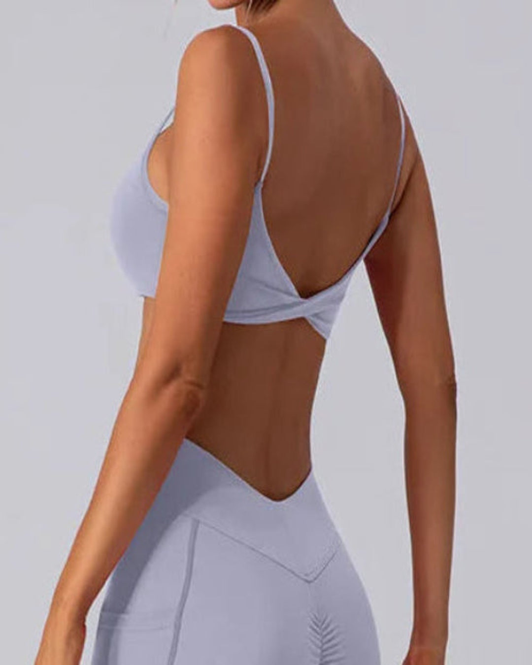 Person wearing a light gray sports bra and leggings set on a plain background